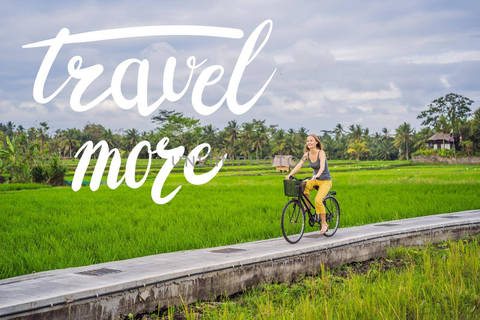 TRAVEL MORE concept A young woman rides a bicycle on a rice field in Ubud, Bali. Bali Travel Concept.