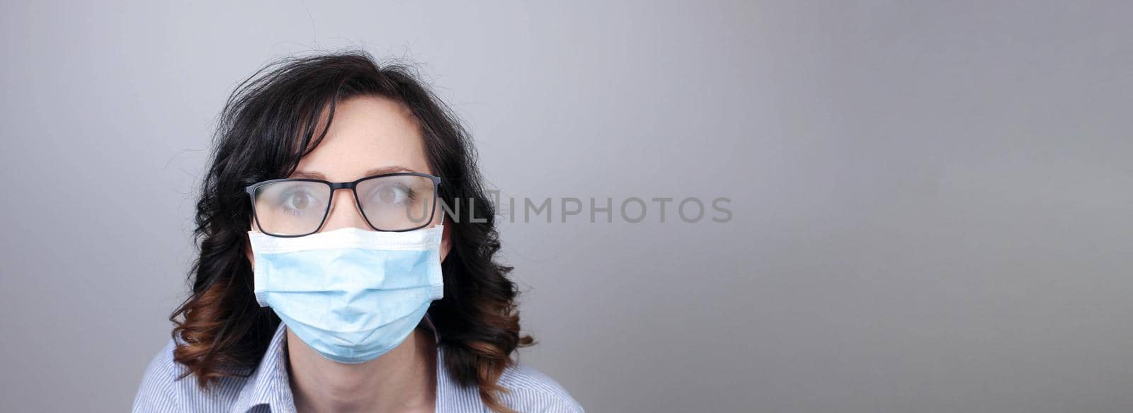 Woman wearing protection face mask against coronavirus and misted glasses. Woman in a mask looking in a mirror. Medical mask, Close up shot, Select focus, Prevention from covid19