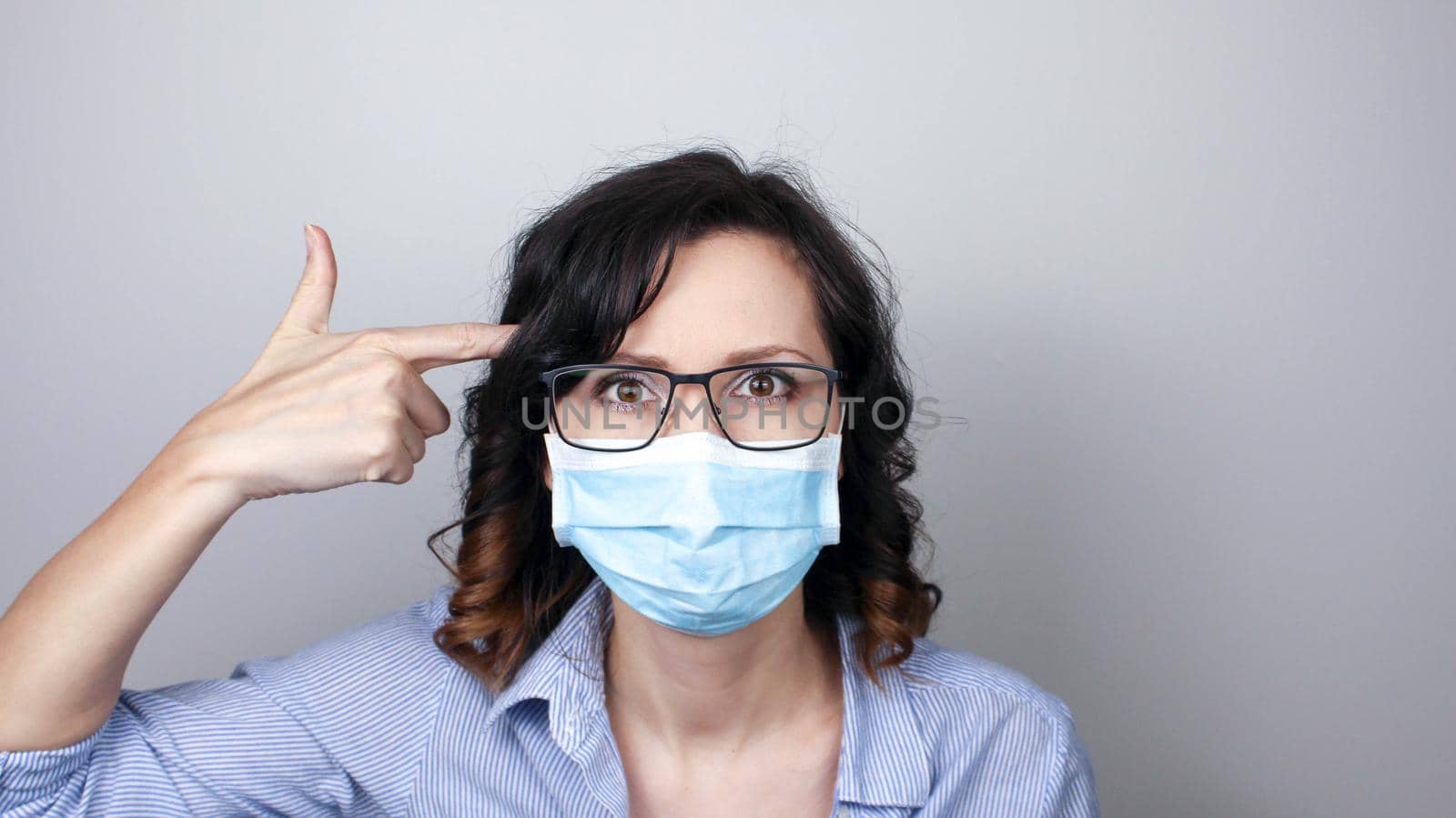 Woman wearing protection face mask against coronavirus and glasses. Woman in a mask showing finger gun. Medical mask, Close up shot, Select focus, Prevention from covid19