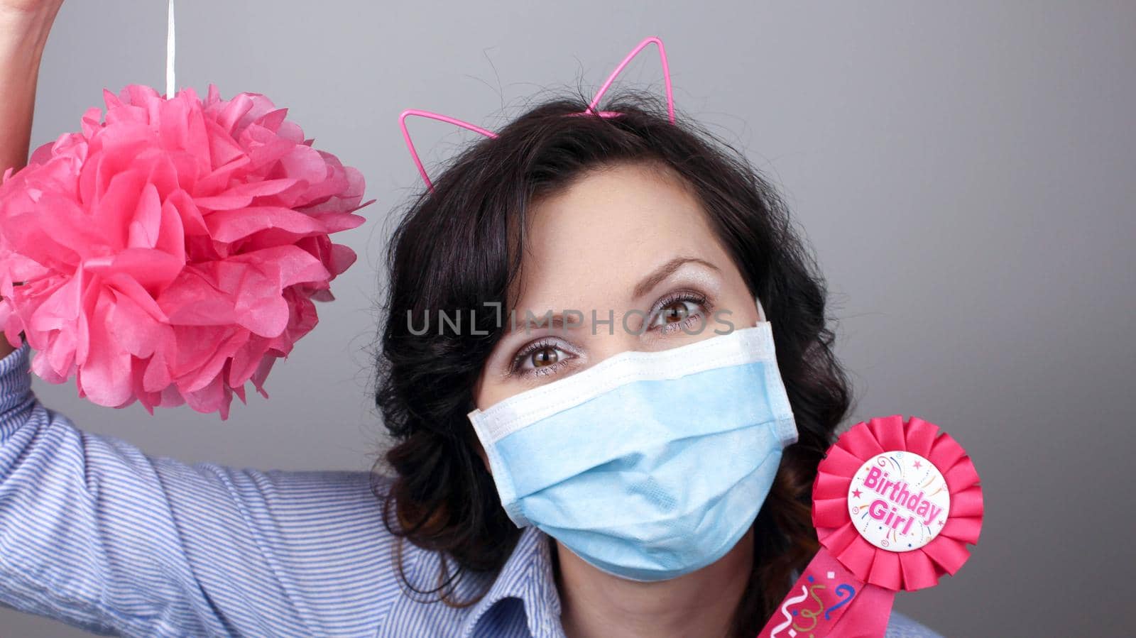 Woman wearing protection face mask against coronavirus. Woman in a mask with party supply. Happy birthday girl with cat ear headband. Medical mask, Close up shot, Select focus, Prevention from covid19