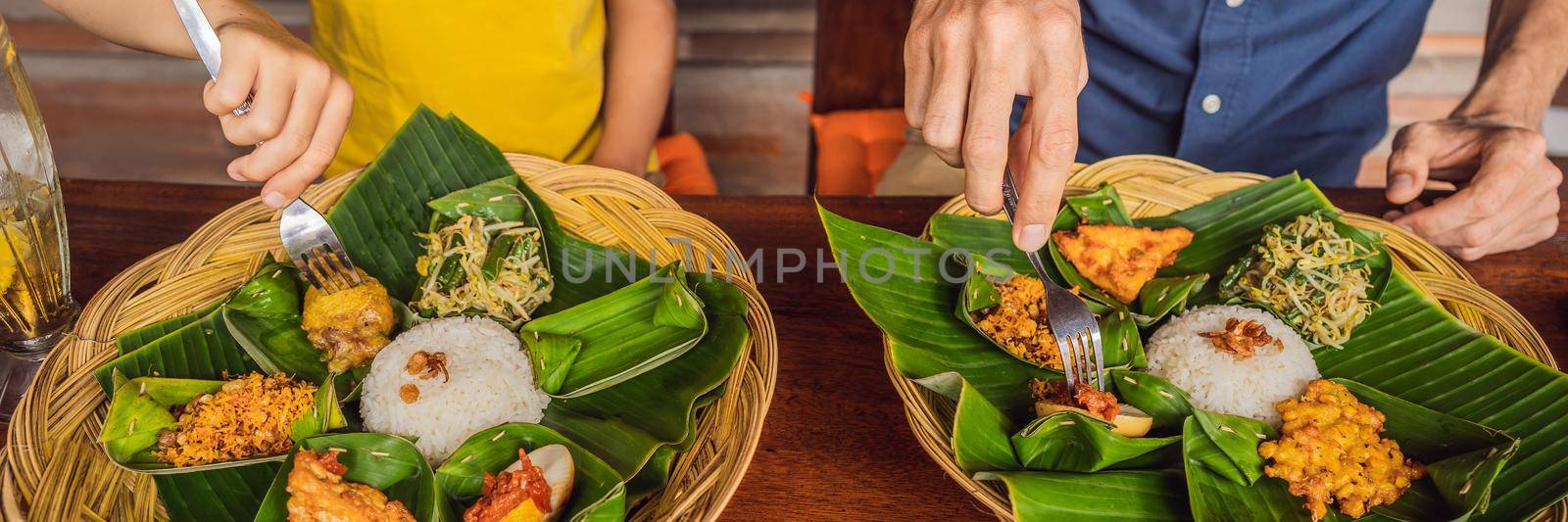 Dad and son tourists in Indonesian food cafe. Traveling with kids concept. What to do with children. Child friendly place BANNER, LONG FORMAT by galitskaya