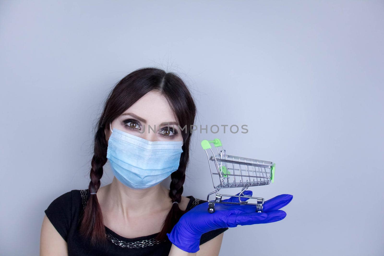 Woman wearing protection face mask against coronavirus. Woman in a mask and holding shopping cart. Medical mask, Close up shot, Select focus, Prevention from covid19