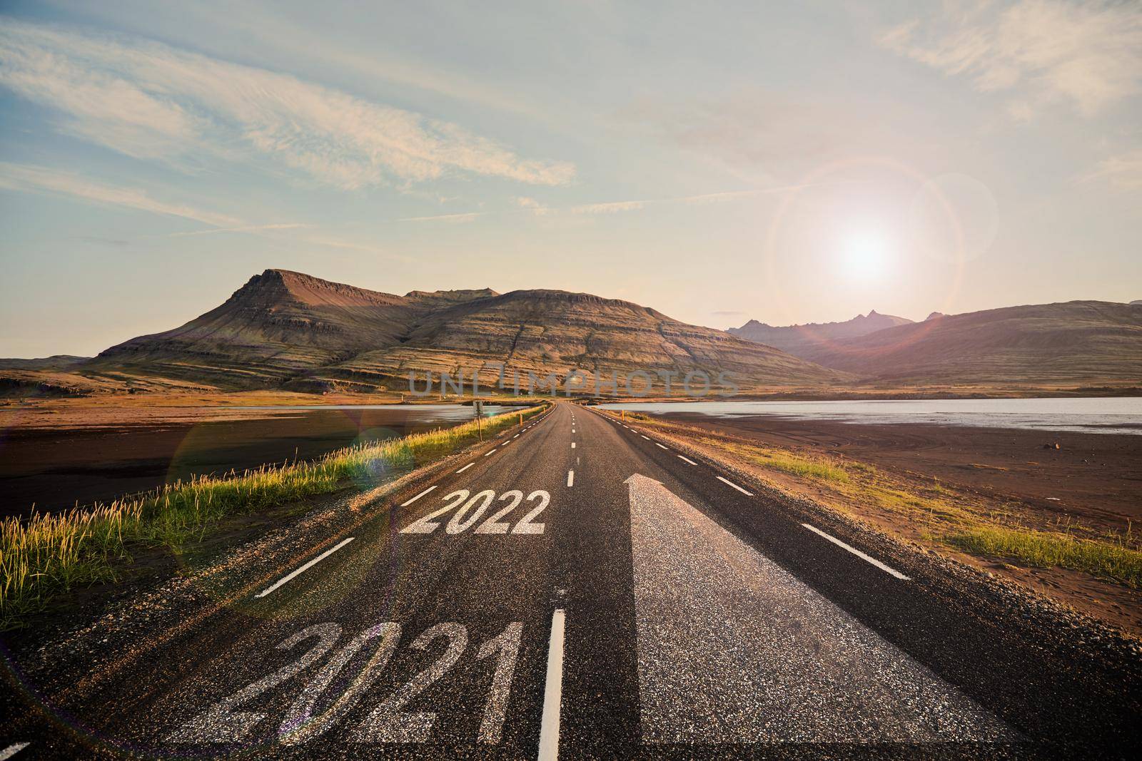 The word 2022 written on highway road in the middle of empty asphalt road at golden sunset and beautiful blue sky. Iceland. High-quality photo