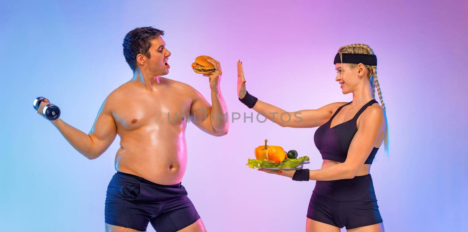 Fat man chooses between burger and fitness with dumbbells. Trainer girl tells him stop and gives vegetables instead of fast food. Not sporty men eating hamburger isolated on pink background. by MikeOrlov