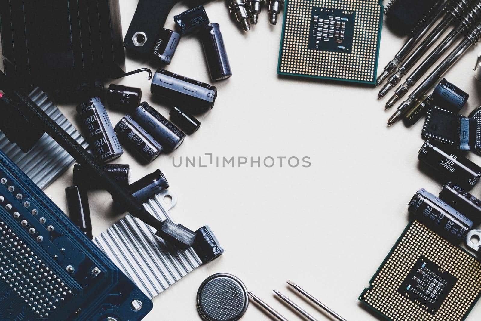 Top view of computer parts with CPU, fan cooler, battery, capacitors, radiator, chip, screwdrivers on white table background with copy space in the center. DIY constructor concept