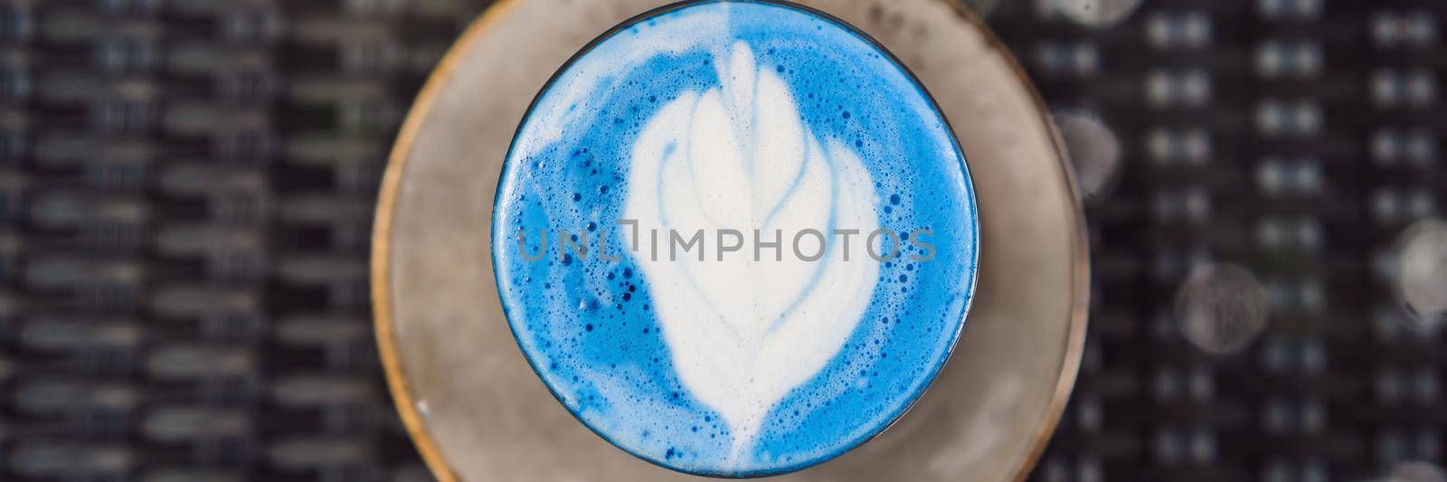 Trendy drink: Blue latte. Top view of hot butterfly pea latte or blue spirulina latte on gray textured background. Copy space for text. BANNER, LONG FORMAT