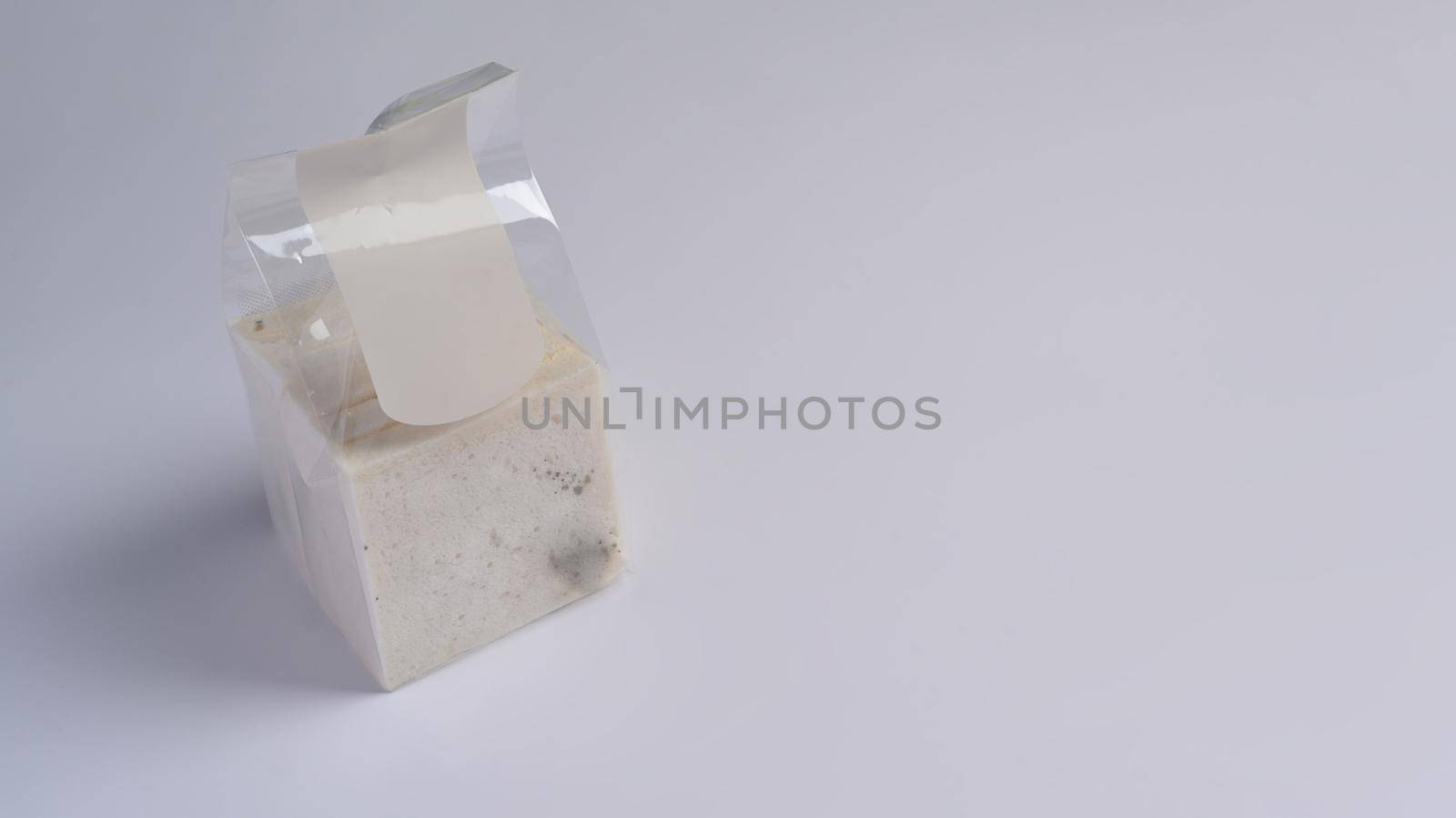 Moldy bread in package on white background.