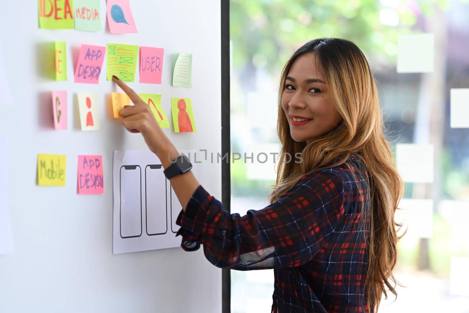 Attractive web developer planning application template layout framework for mobile phone on whiteboard.