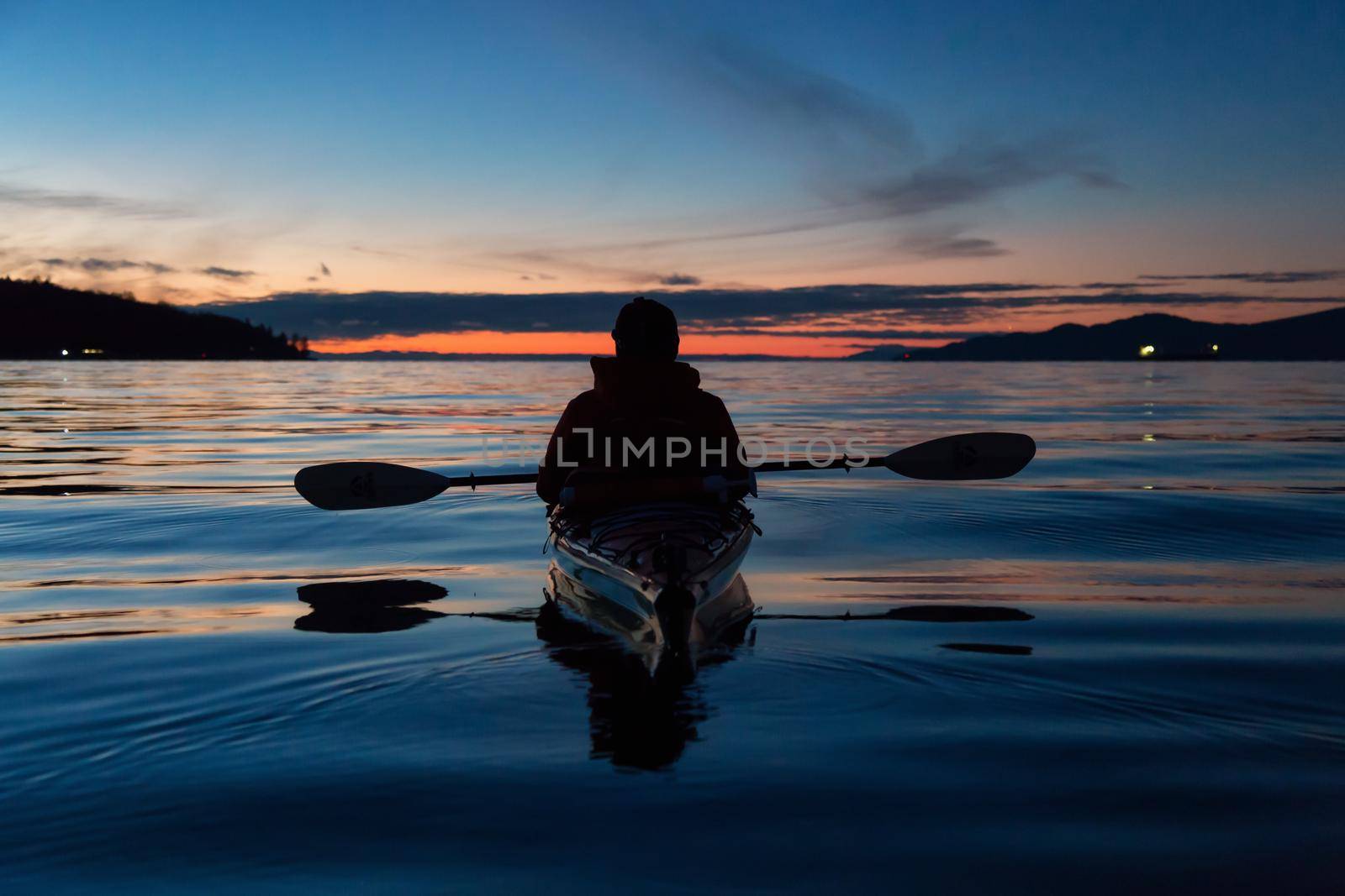 Man Kayaking on a sea kayak during a vibrant sunset. Taken near Jericho Beach, Vancouver, British Columbia, Canada.