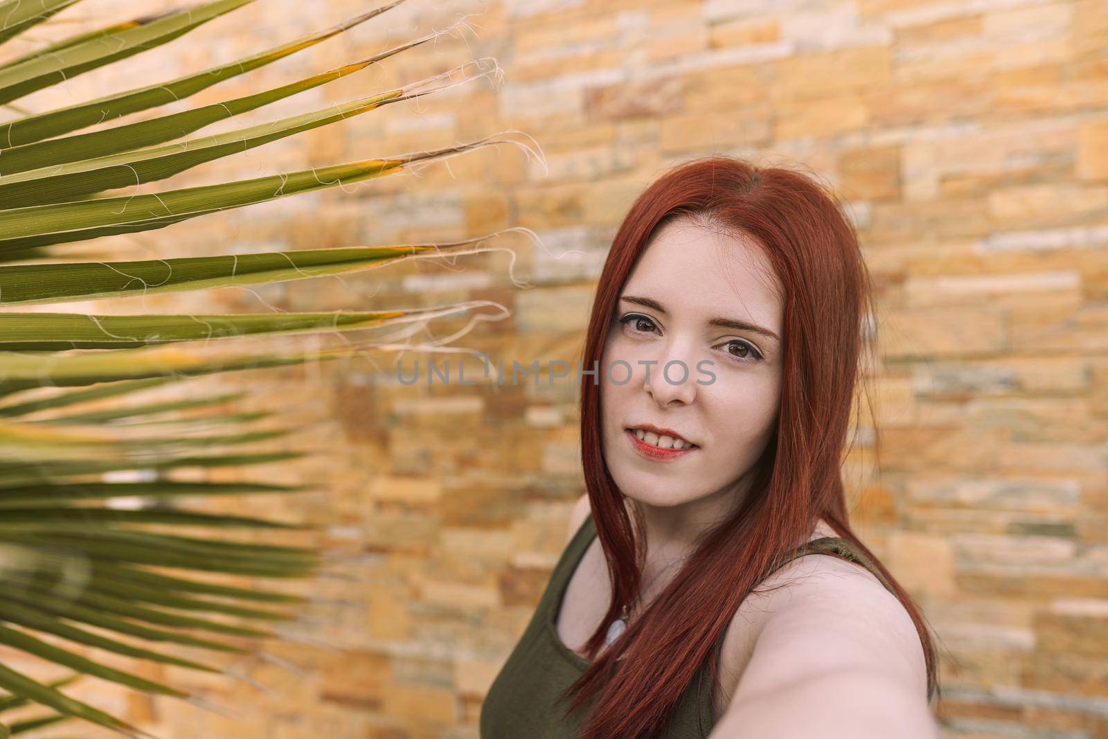 young woman taking a selfie with her cell phone on her summer vacation. tourist in hotel. self portrait in the foreground. by CatPhotography