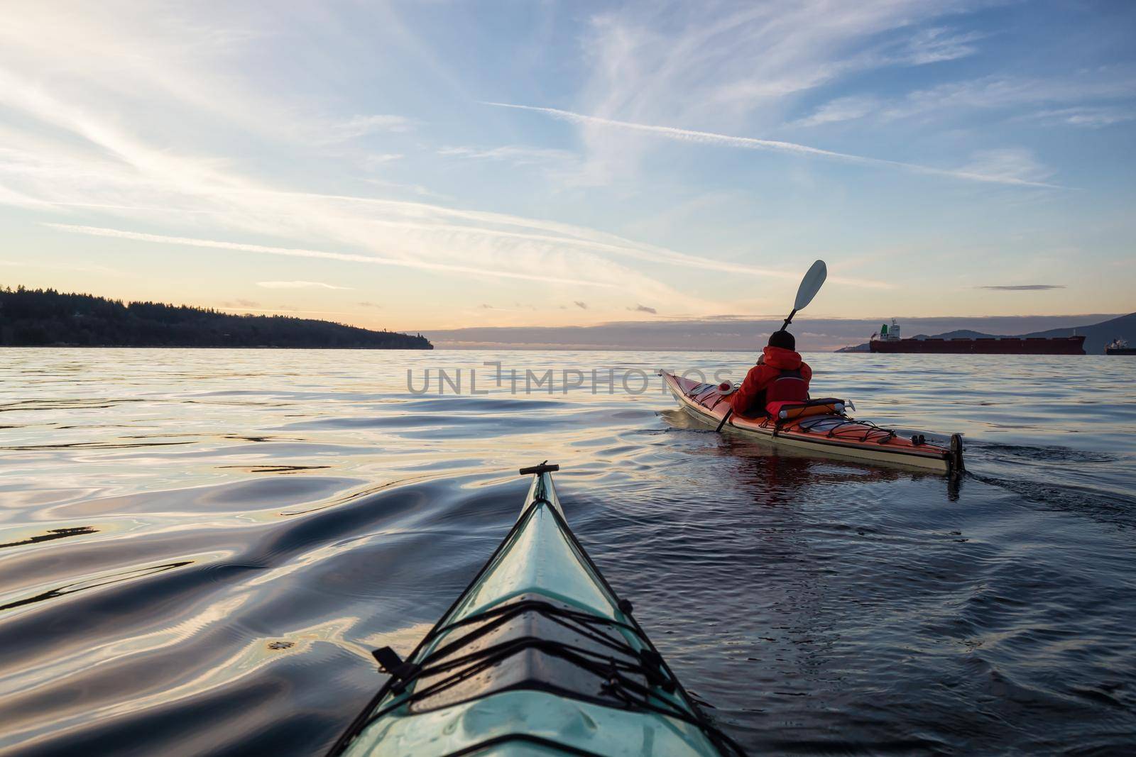 Adventure Man on a Sea Kayak is kayaking during a vibrant and colorful winter sunset. Taken in Vancouver, British Columbia, Canada. Adventure, Vacation Concept