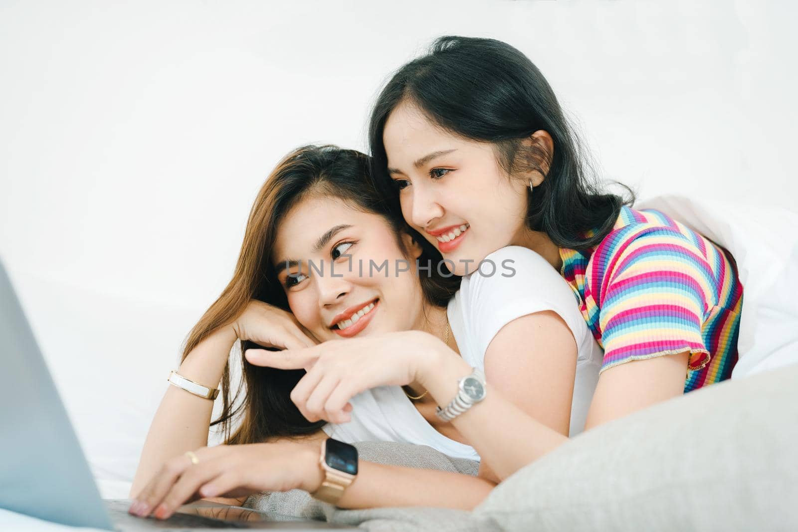 lgbtq, lgbt concept, homosexuality, portrait of two asian women posing happy together and loving each other while playing computer laptop on bed by Manastrong