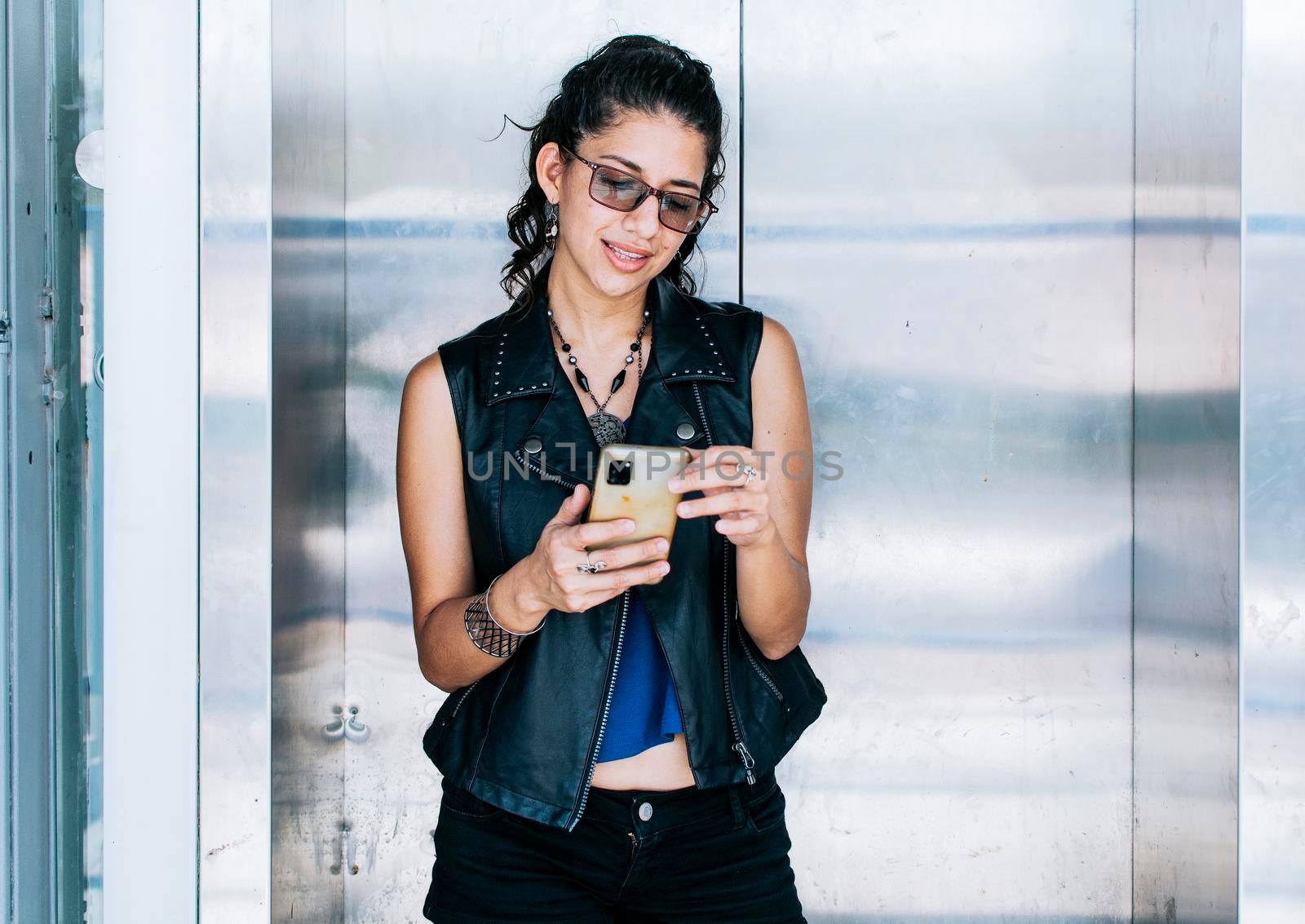 Attractive girl using her cell phone at the elevator door, A person texting in the elevator, Close up of urban girl checking her cell phone by isaiphoto