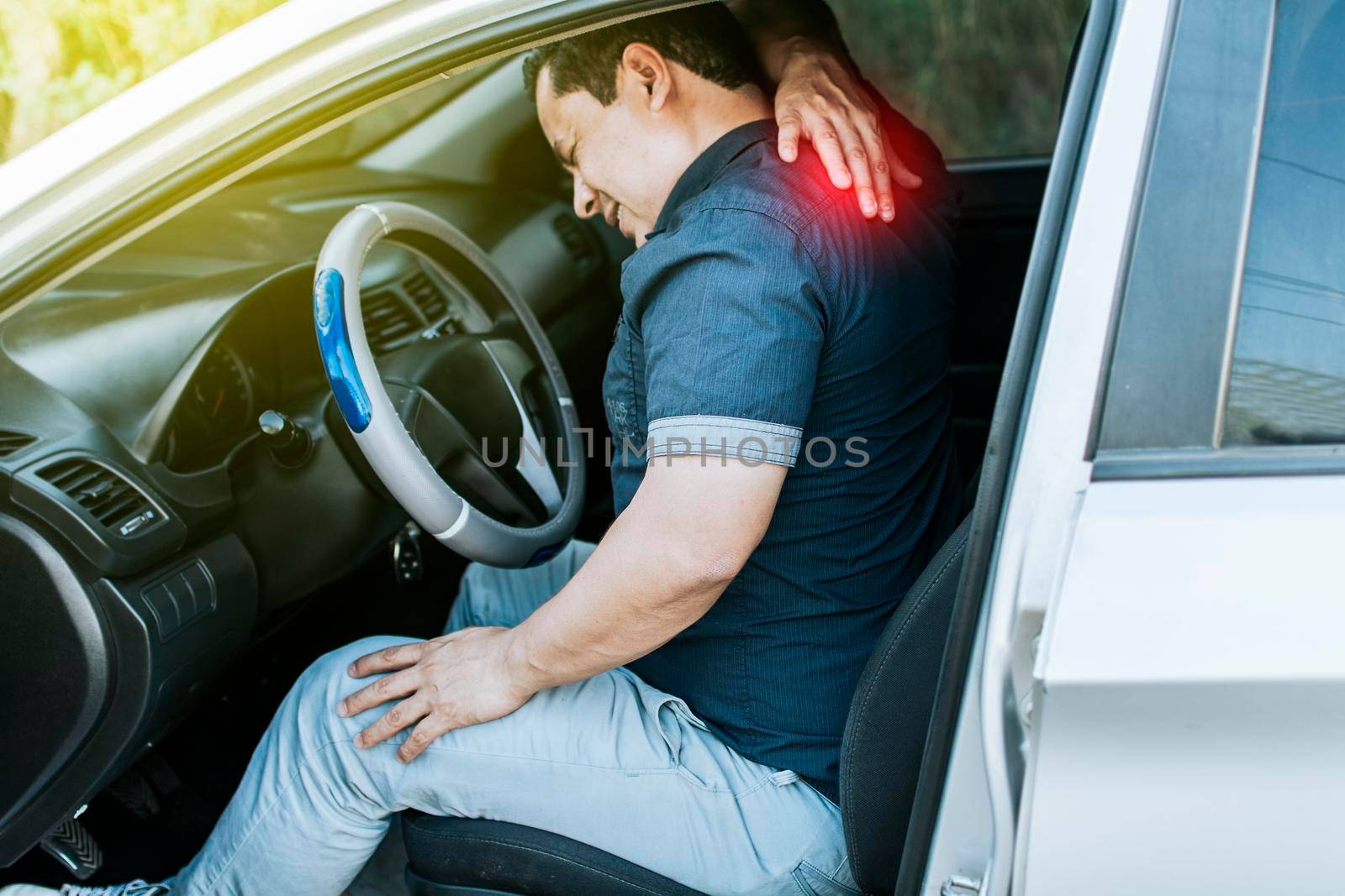 A car driver with muscle pain, concept of a man in his car with neck pain. An exhausted driver with back pain, A person with muscle pain in traffic by isaiphoto
