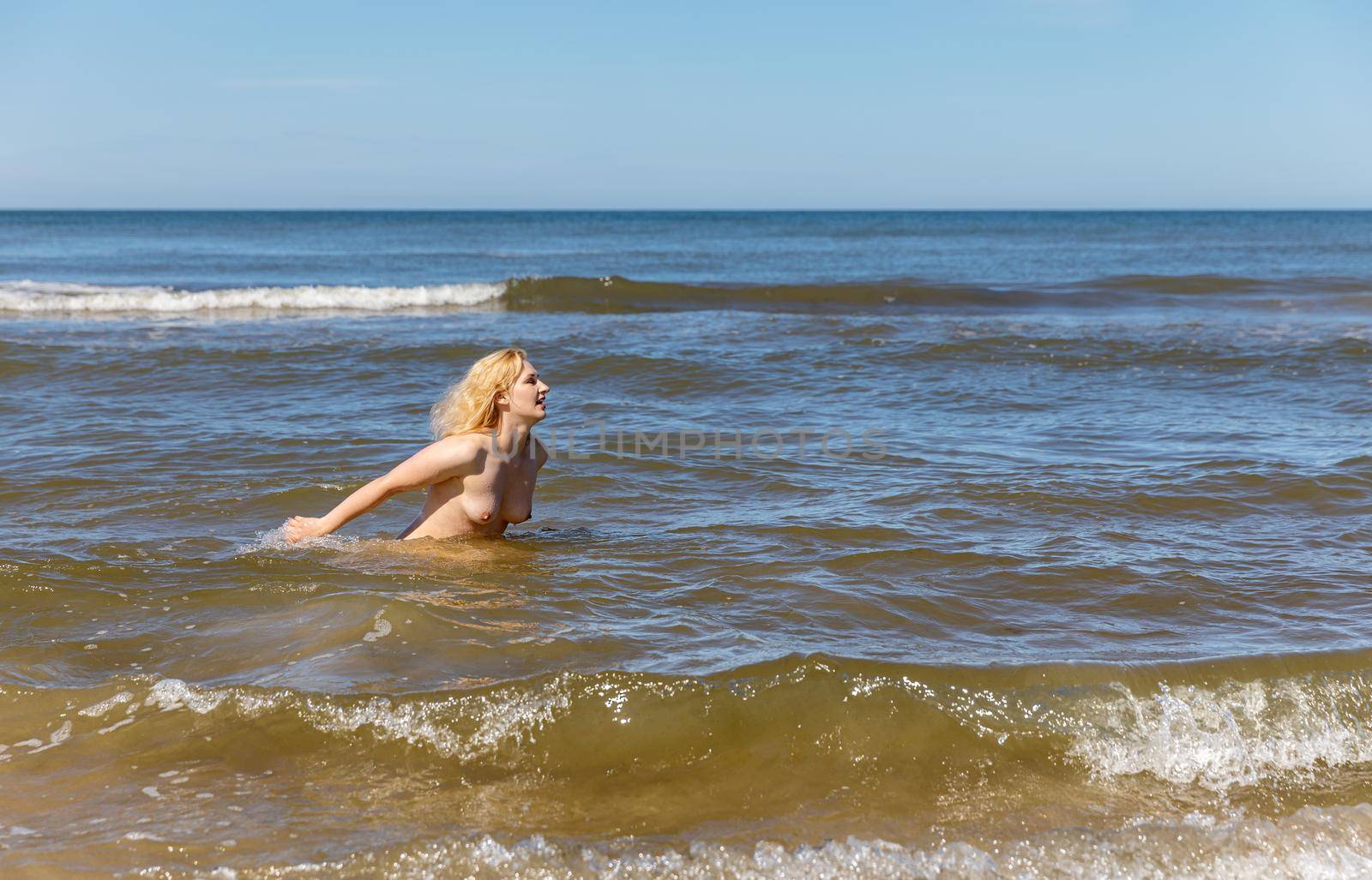 Naked blonde woman enjoys nature on the seashore by palinchak