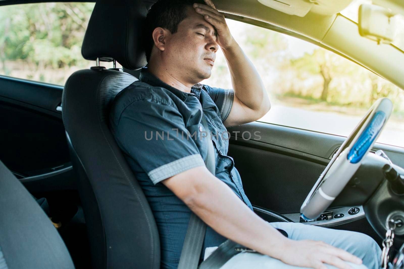 A person in his car with a headache, Concept of a man in his car with a headache, A car driver with a headache, A driver with stress and migraine by isaiphoto