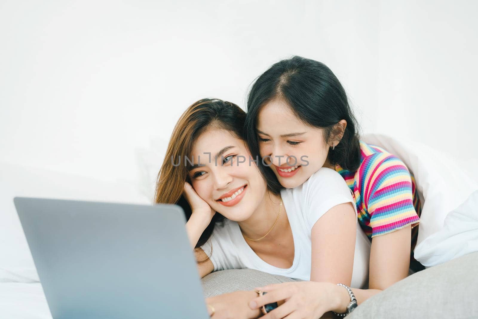 lgbtq, lgbt concept, homosexuality, portrait of two asian women posing happy together and loving each other while playing computer laptop on bed by Manastrong