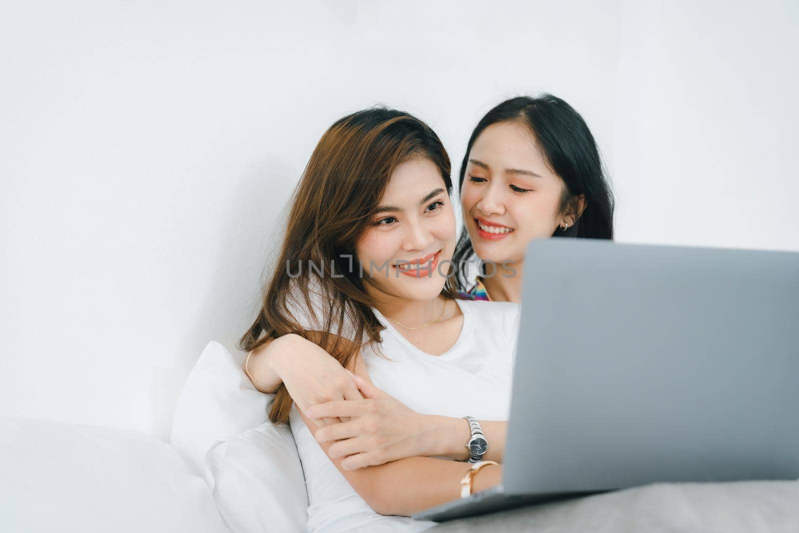 lgbtq, lgbt concept, homosexuality, portrait of two asian women posing happy together and loving each other while playing computer laptop on bed by Manastrong