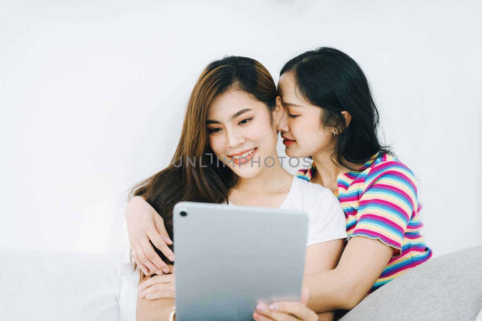 lgbtq, lgbt concept, homosexuality, portrait of two asian women posing happy together and loving each other while playing tablet on bed by Manastrong