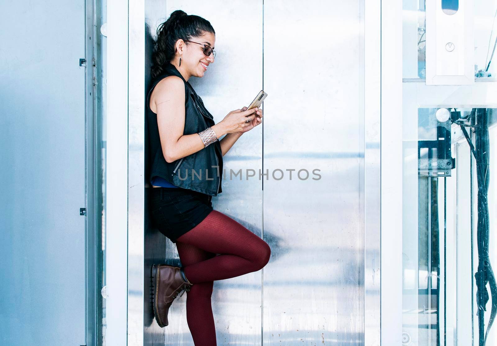 A person texting in the elevator, Attractive girl using her cell phone at the elevator door, Close up of urban girl checking her cell phone