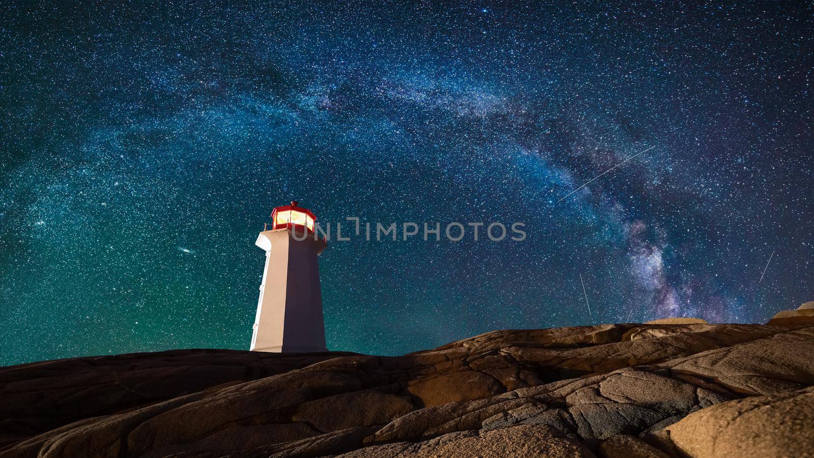 Lighthouse surrounded by rocks at night, lighthouse with lights on at night
