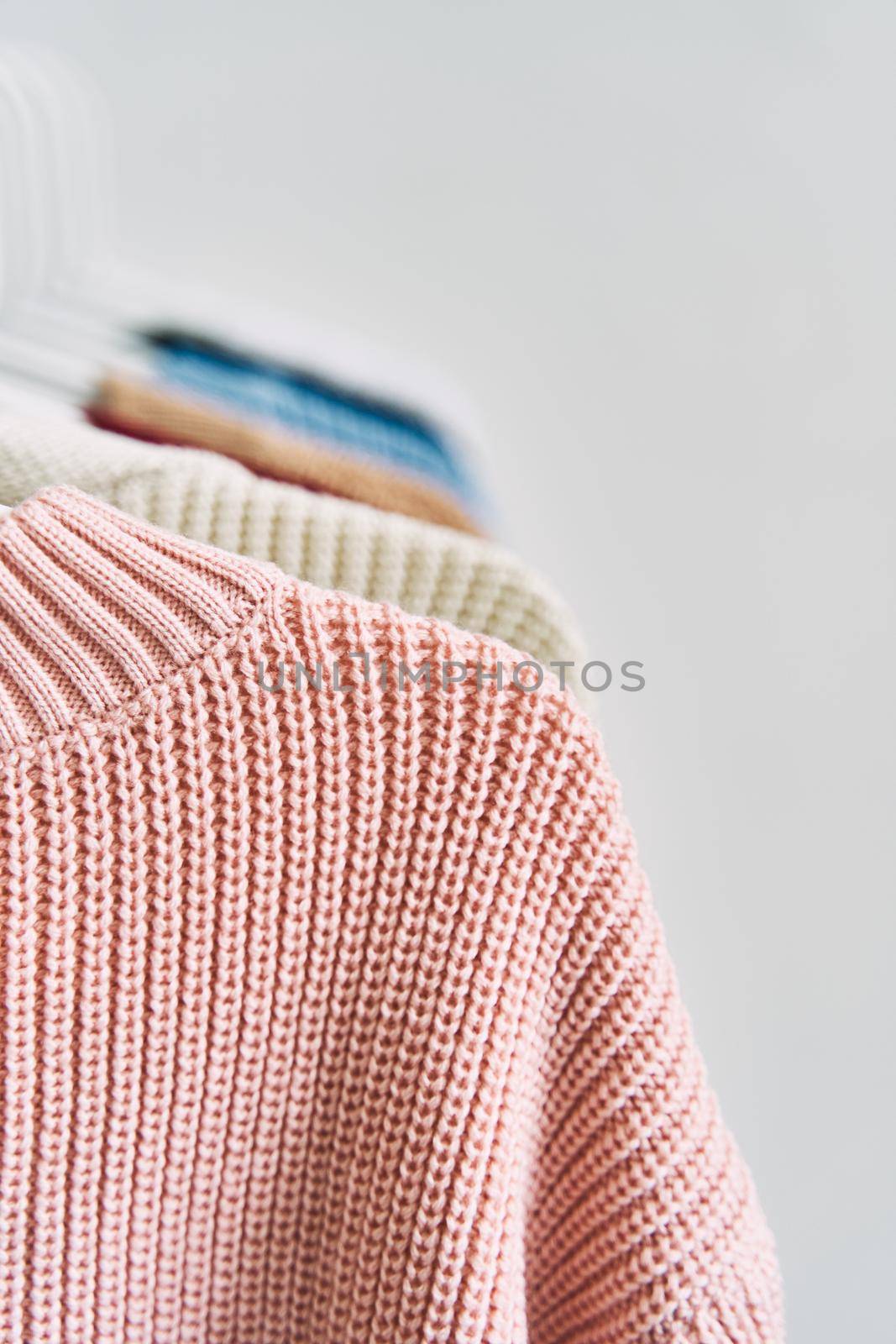 multicolored women's woolen sweaters on hangers. Sale in a fashion store. High quality photo