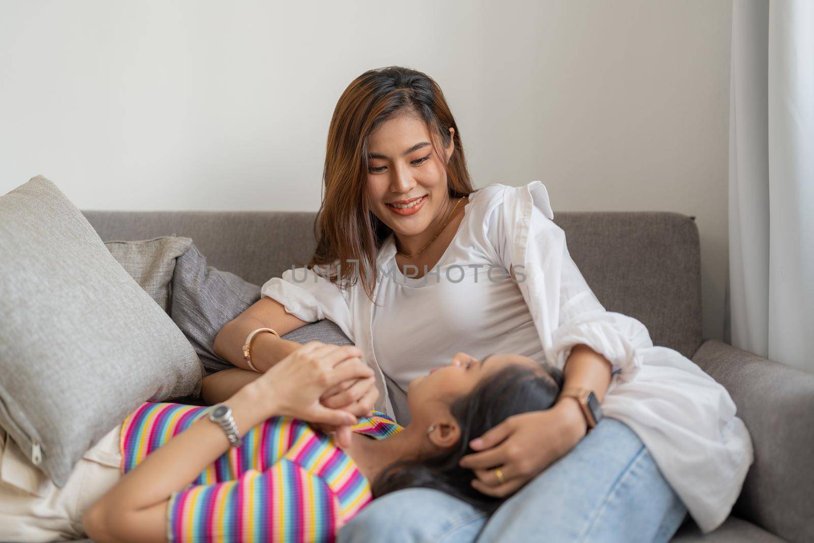 Two happy young aisan casual women having fun on couch at home. Lesbian millennial couple. gbt, homosexual, lesbian couple lifestyle by nateemee