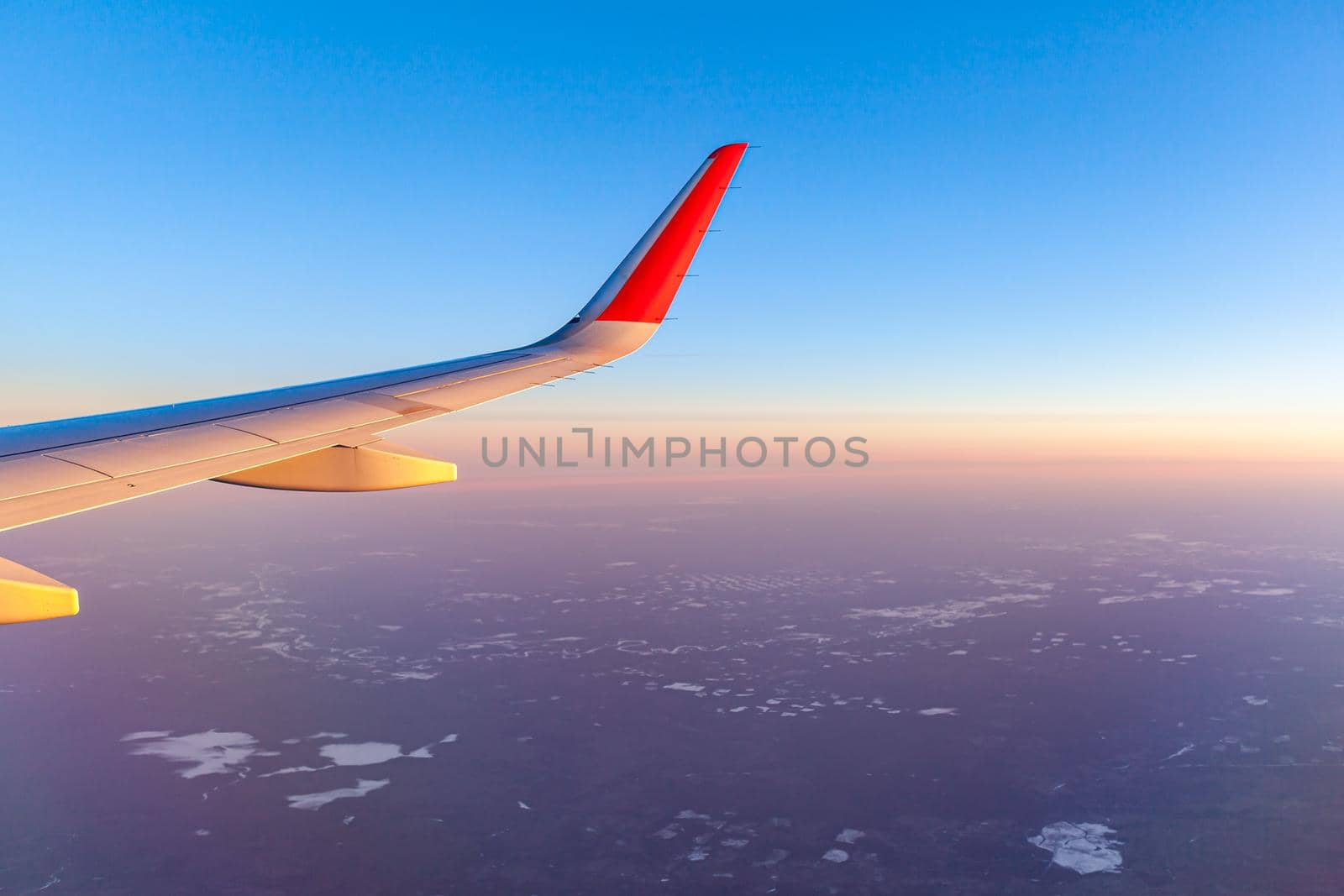 Airplane flight. Aircraft's wing and land seen through the illuminator by AnatoliiFoto