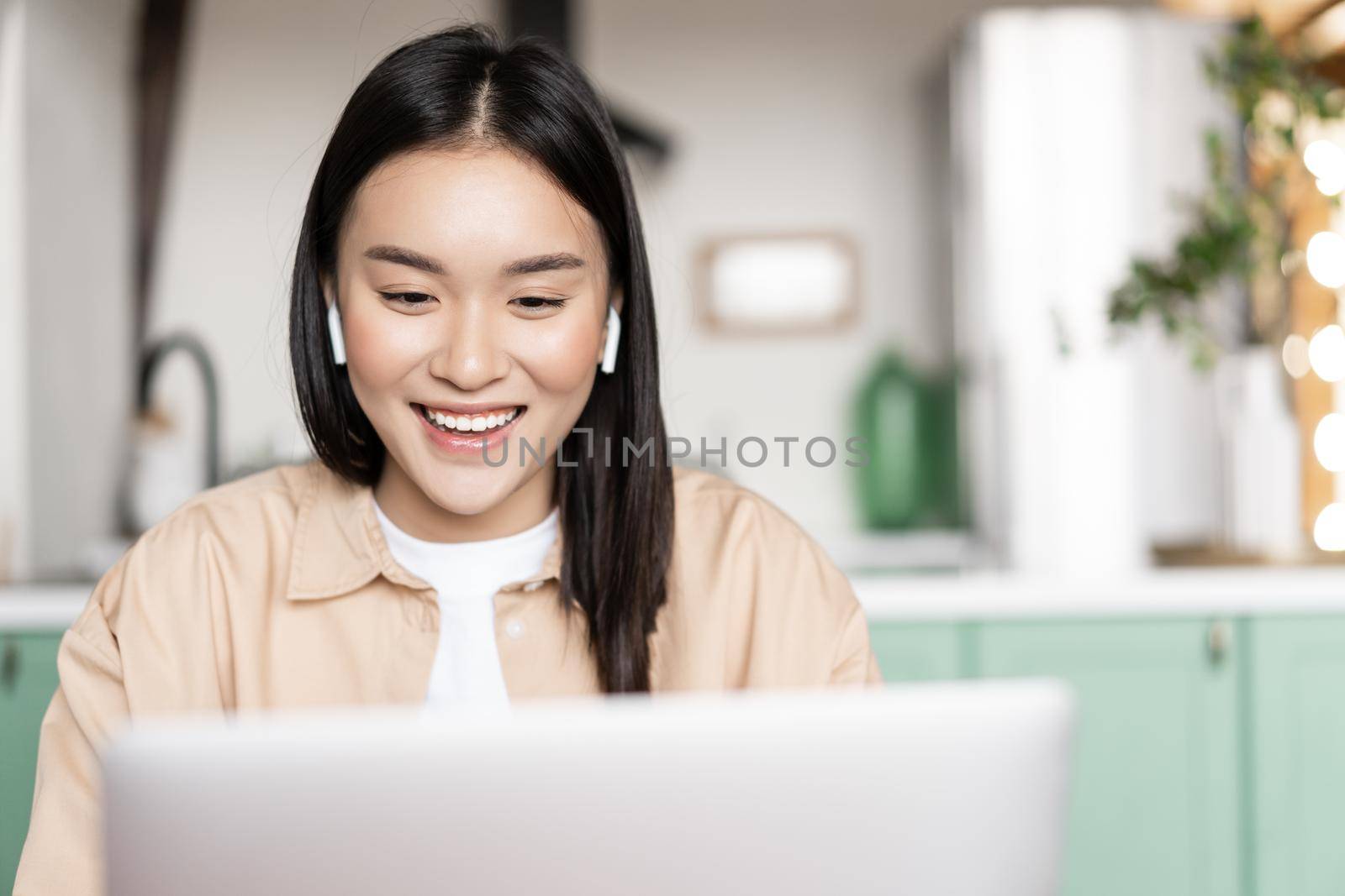Smiling asian girl listening, watching on laptop, looking at computer during online webinar. Concept of remote education or work.