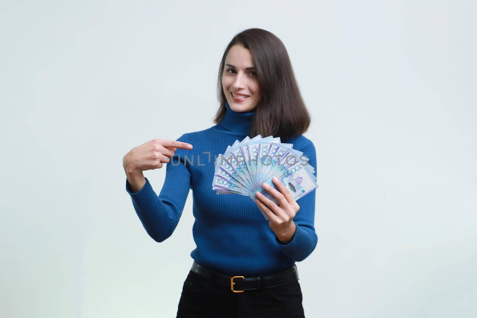 Sly girl holds a lot of tenge money in her hands.