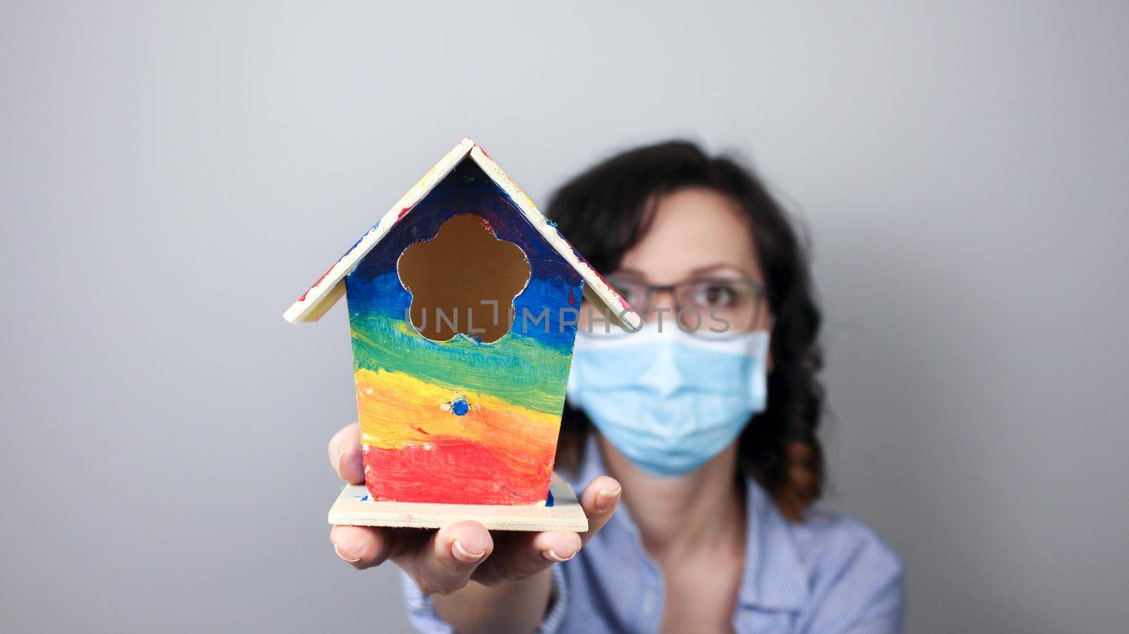 Woman wearing protection face mask against coronavirus and glasses. Woman in a mask showing rainbow house. We will be okay. Medical mask, Close up shot, Select focus, Prevention from covid19