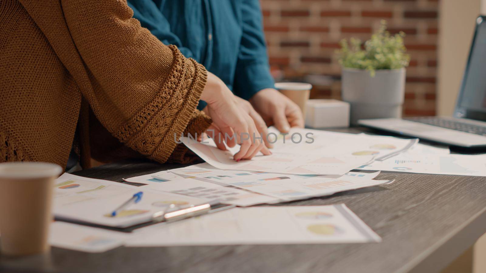 Close up of business people looking at papers with rate charts to plan project and presentation at desk. Colleagues working together with information files to design marketing strategy