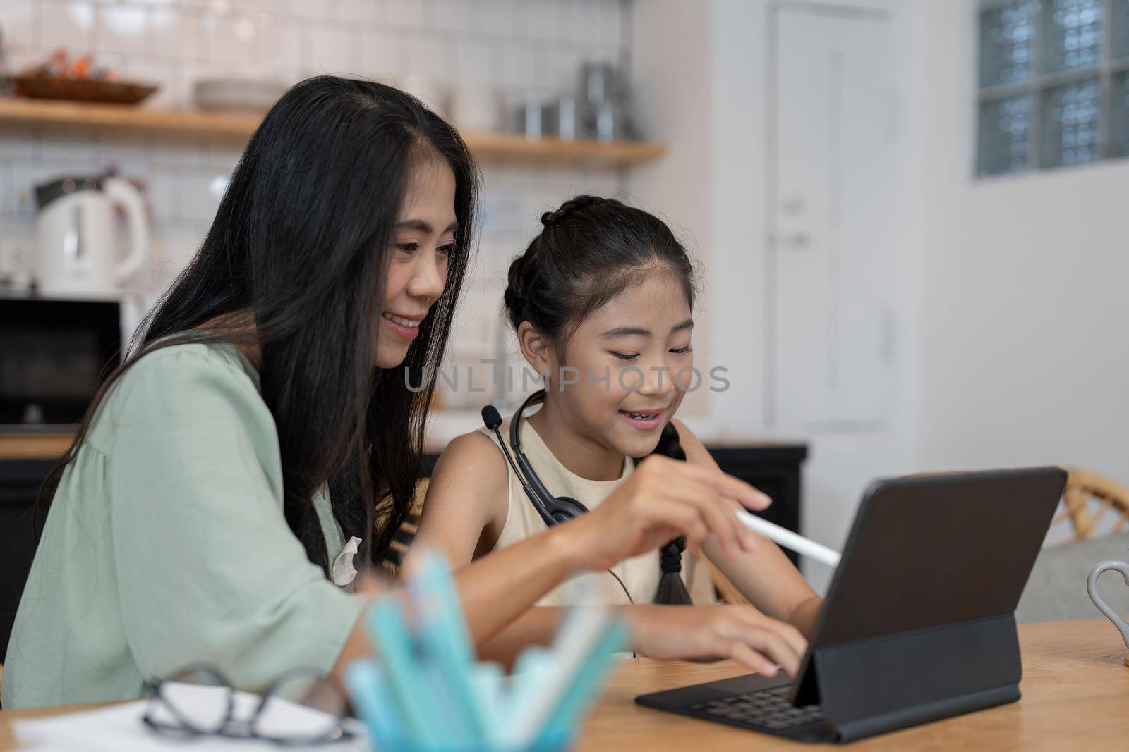Asian young mother with computer notebook teaching kid to learn or study online at home, Homeschooling online concept.