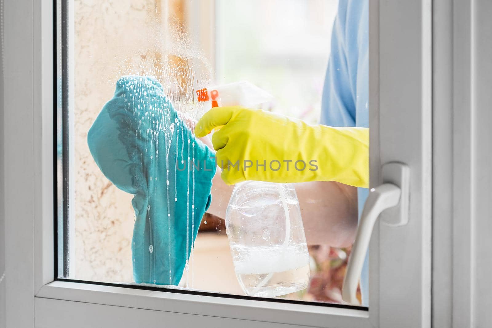 Man cleaning window with the detergent and rag by Syvanych