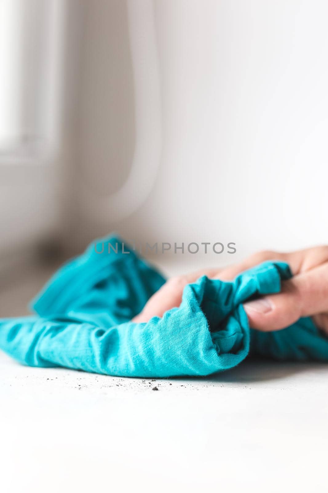 Man cleaning the windowsill with a blue cloth. Doing chores at home
