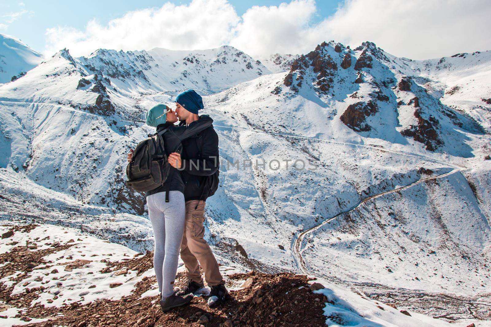 A kiss between a man and a woman amid snow mountains. Holiday in mountains.