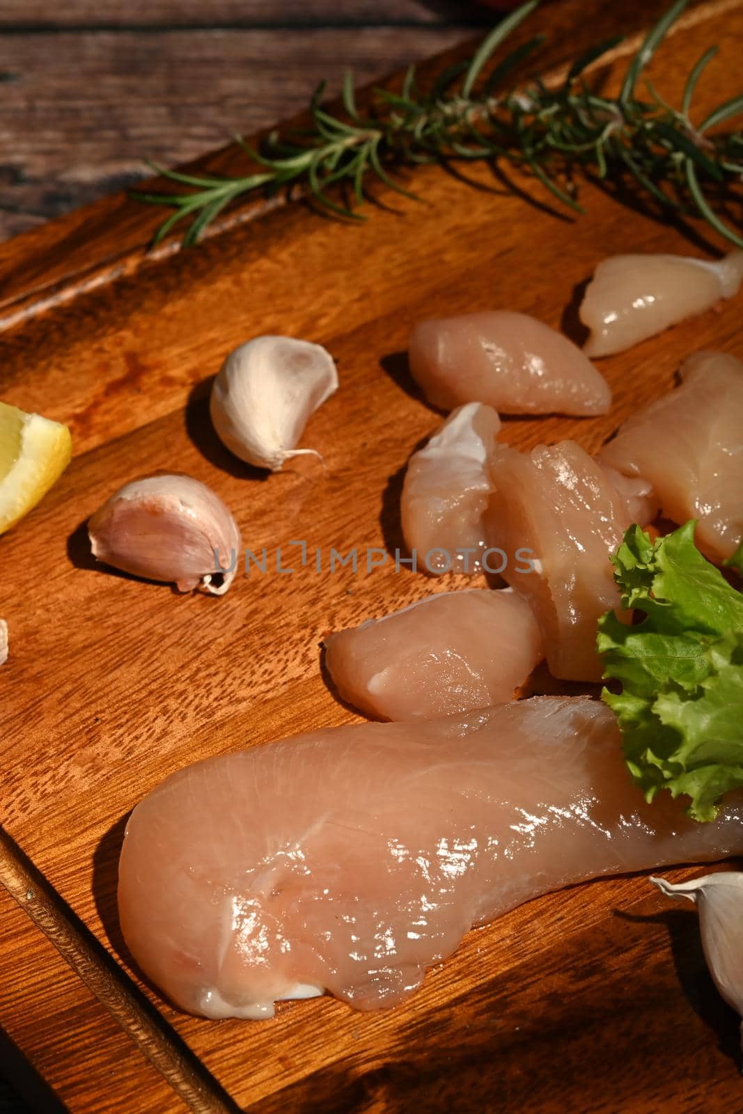 Raw chicken with spices, herbs and vegetables on cutting board ready for grilling. Selective focus.