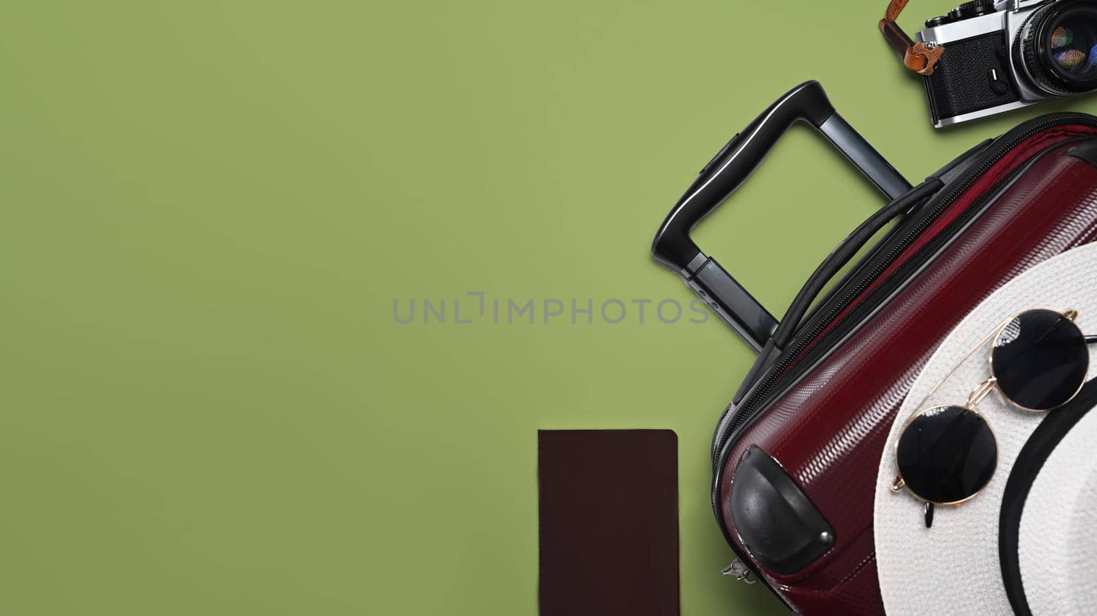 Suitcase, smart phone, sunglasses, camera and passport on green background for summer holidays. Top view with copy space.