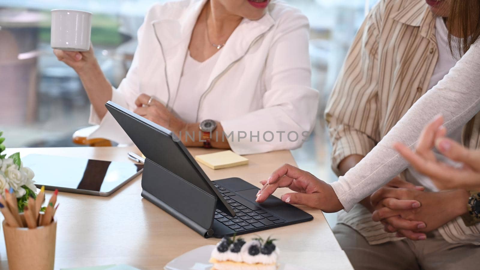 Cropped shot of middle aged female team leader discussing new ideas with employees in meeting.