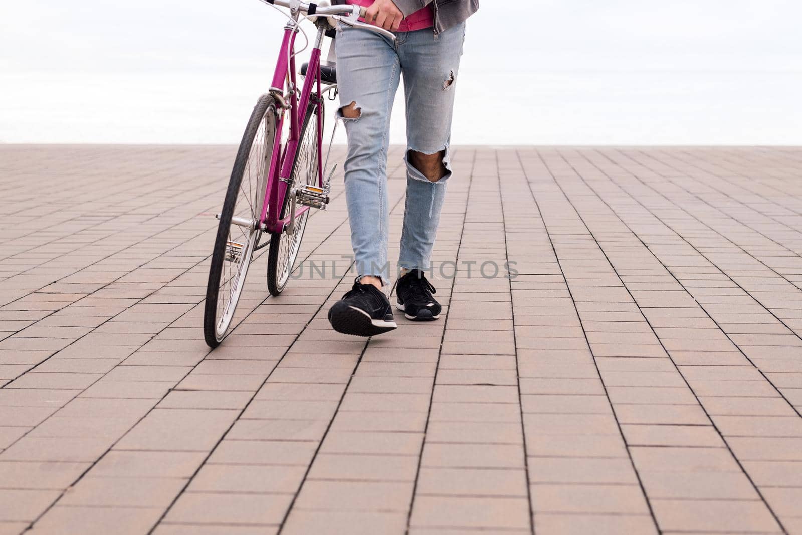 unrecognizable young man walking pushing a bicycle, concept of ecological and sustainable transportation, copy space for text