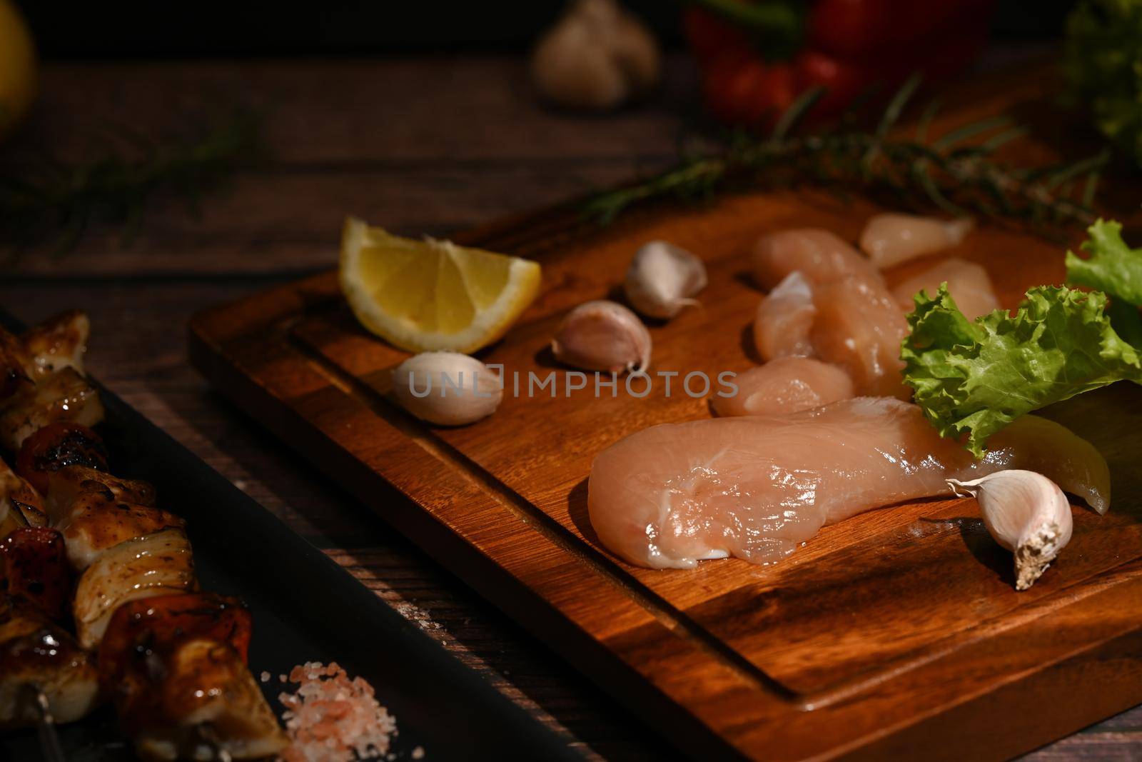 Raw tender chicken on cutting board with spices, herbs and vegetables for grill and bbq. Selective focus.