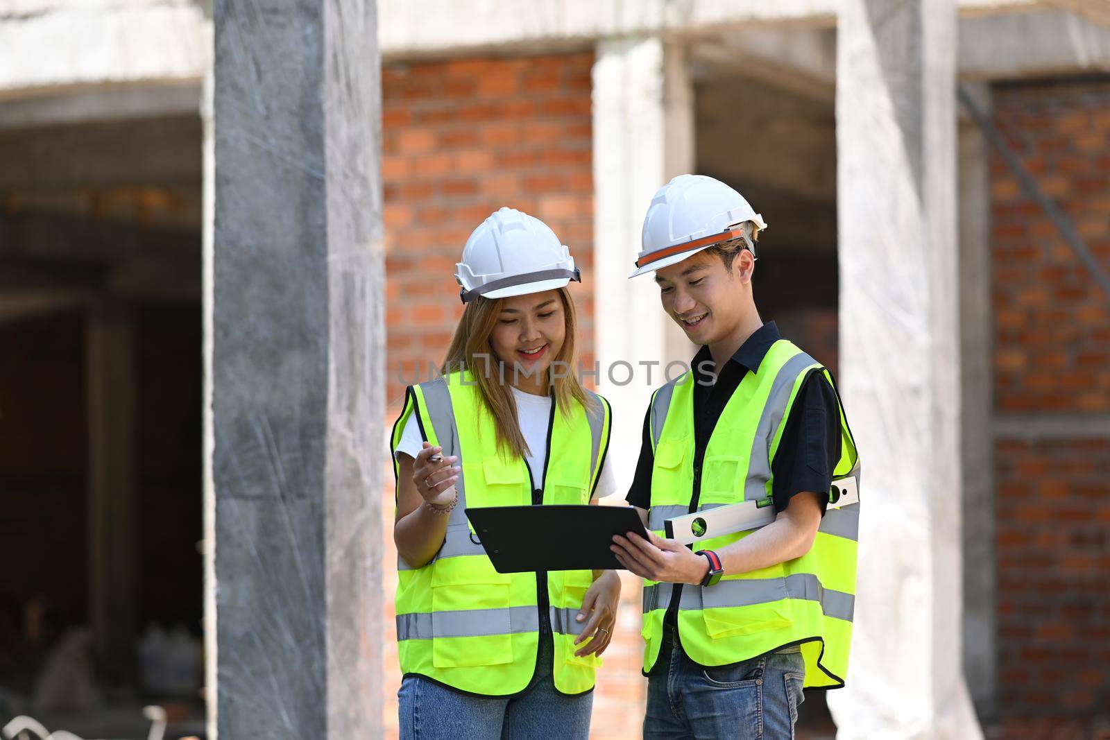 Engineer managers wearing safety vest and helmet working together at construction site by prathanchorruangsak