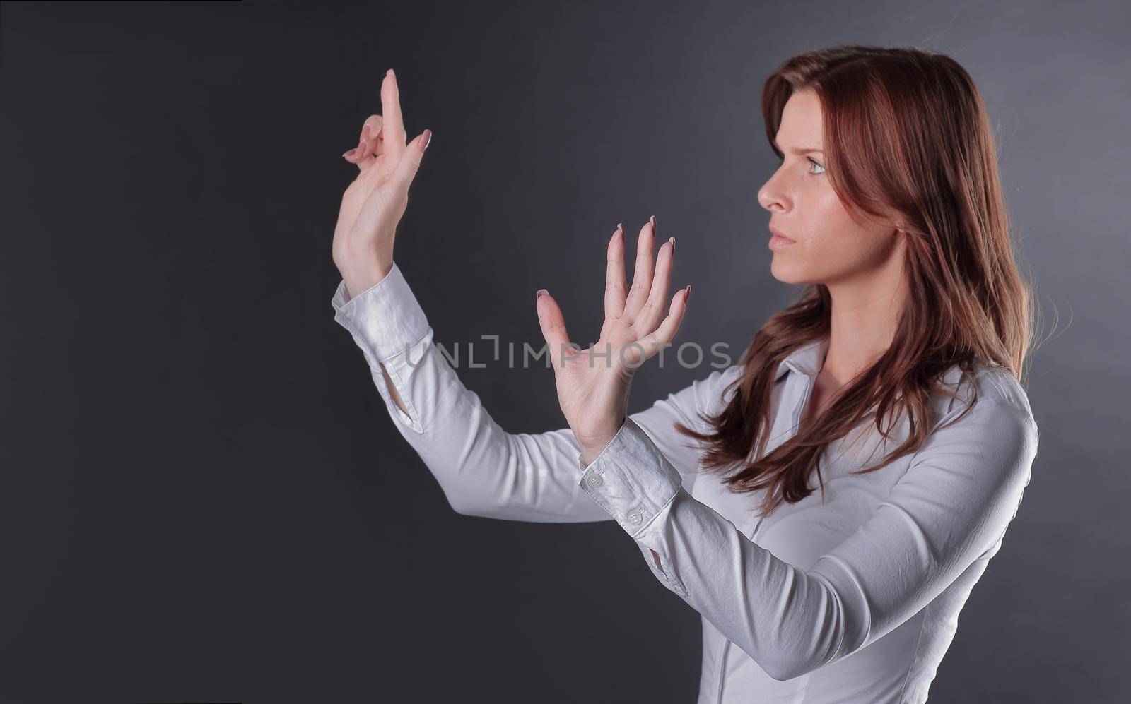 uncertain business woman clicks on the virtual button.isolated in the dark.photo with place for text