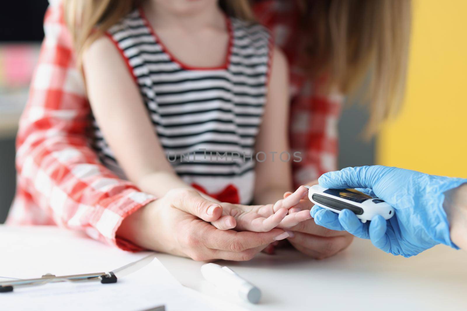 Close-up of doctor in laboratory taking blood of little girl thumb using lancet in clinic, standard procedure for checkup, analysis. Medicine, hospital, pediatrician appointment concept