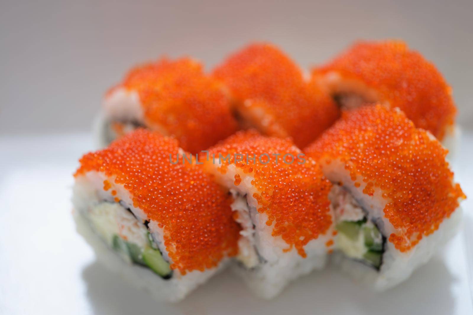 Sushi with orange flying fish caviar on a white plate, close-up. Specific taste, national Japanese cuisine