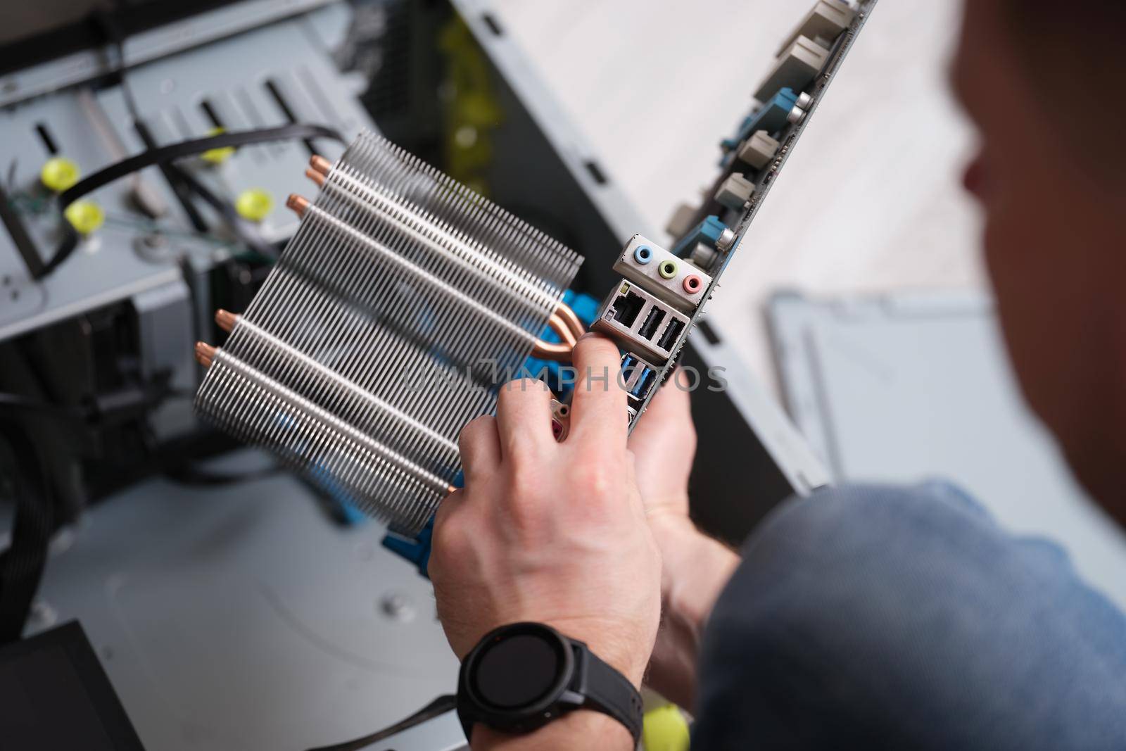 A man holds a motherboard, hands close-up. Repair and maintenance of electronics, replacement of computer components