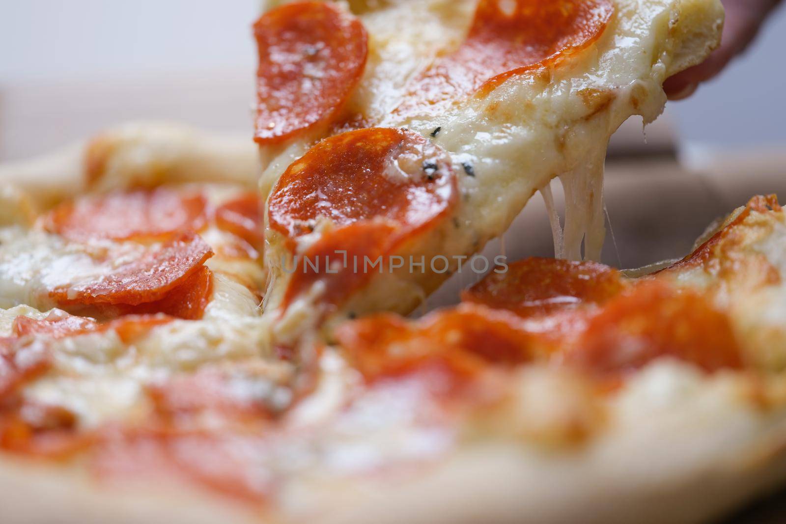 A man takes a large slice of hot neo-Politan pizza, close-up. Sausage with melted cheese on a flatbread, fast food