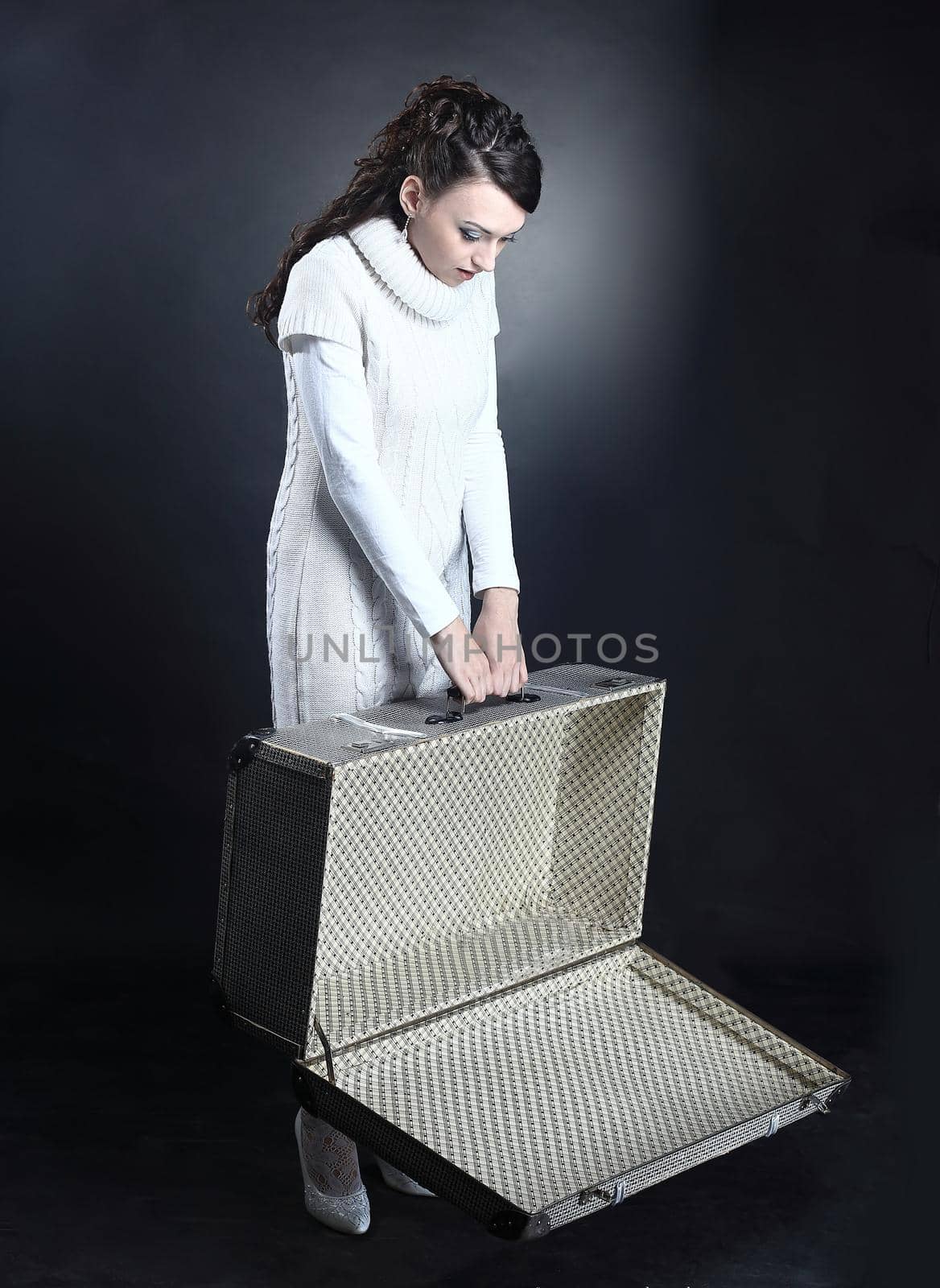 upset young woman with an empty suitcase.isolated on a black