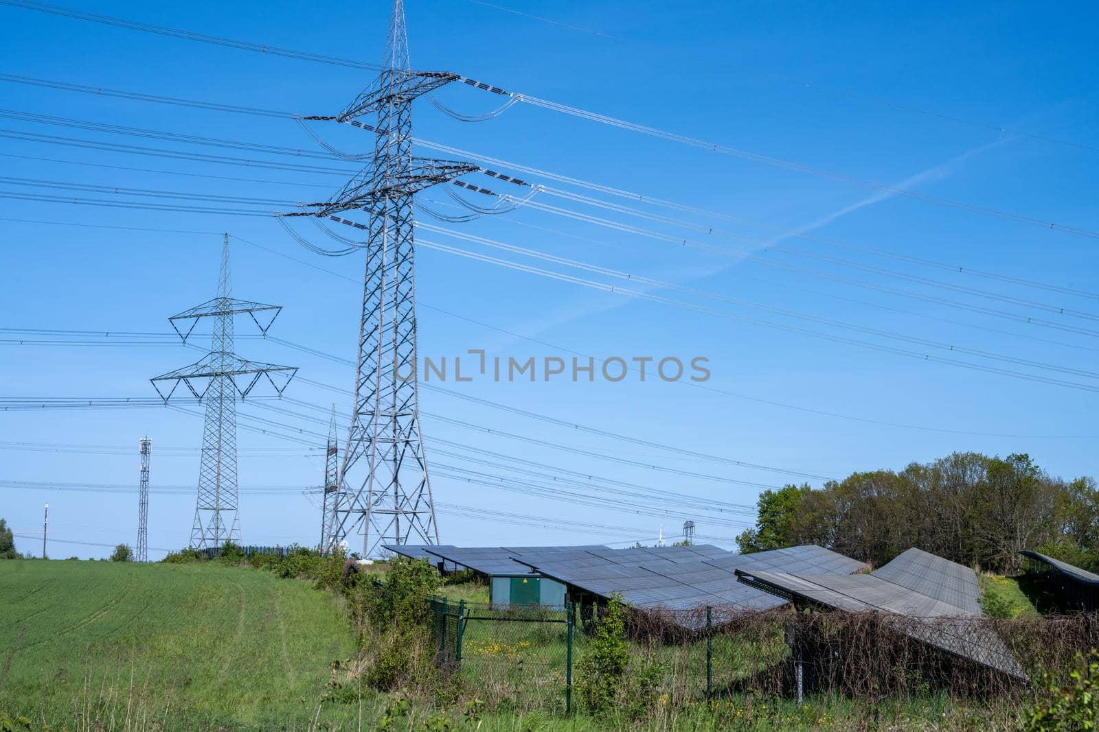 Power lines with pylons and a solar power plant by elxeneize