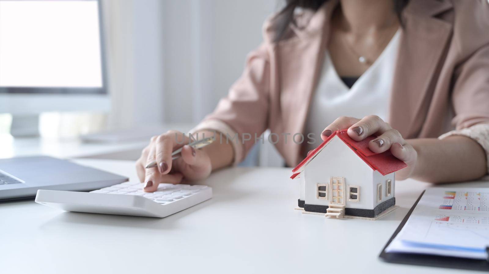 Businesswoman using calculator calculating account for buy house in the future. Property investment concept.
